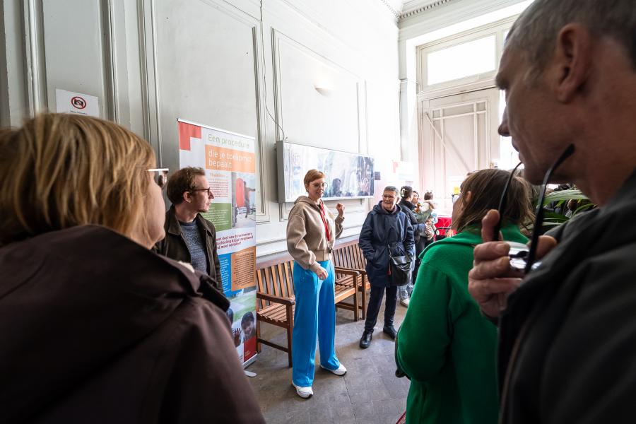 Een gids neemt een groep mensen mee op rondleiding doorheen het gebouw van het Rode Kruisopvangcentrum.