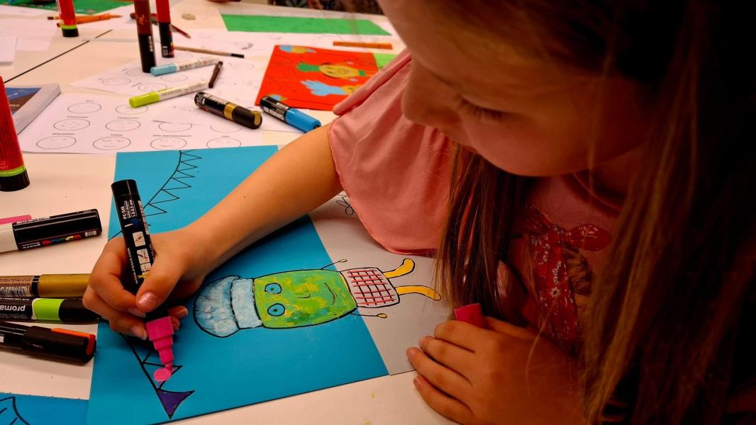 Kind met stiften tekent cartoon op gekleurd papier